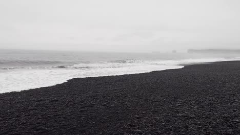 black sand beach, reynisfjara beach, iceland in rainy autumn - panning shot