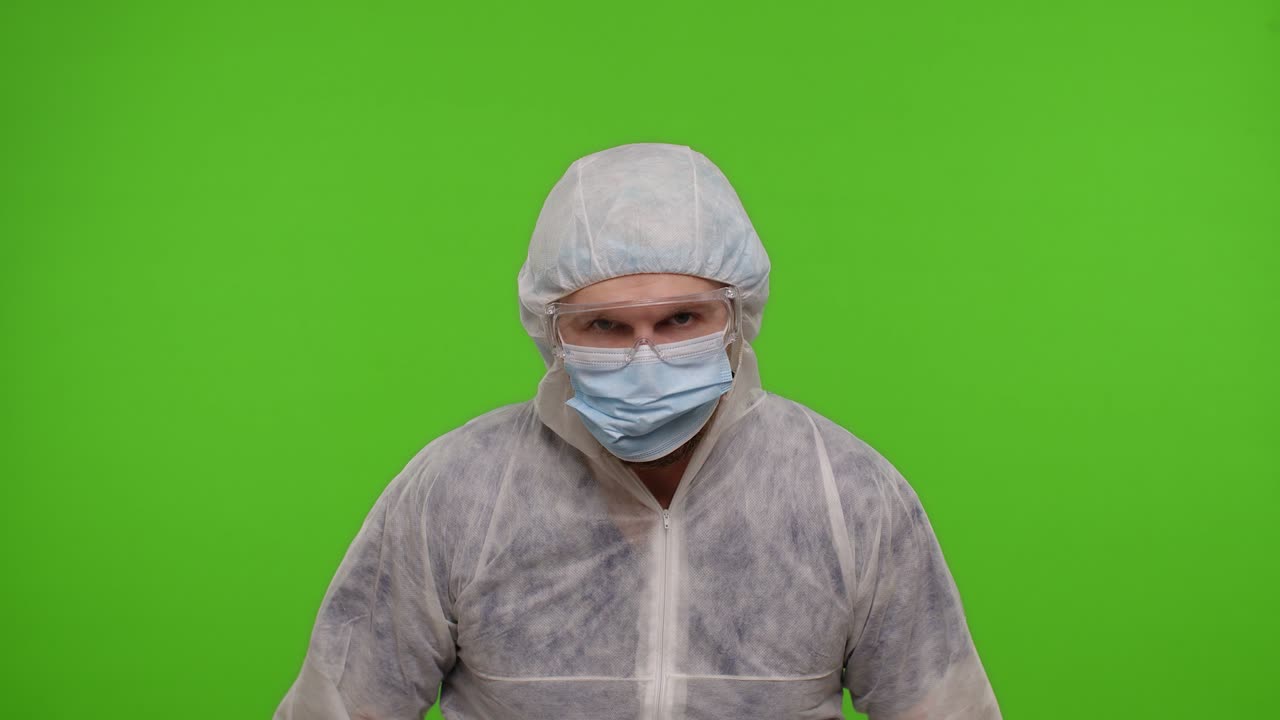 두 개의 주사기를 가진 ppe 보호복을 입은 미치광이 의사는 춤추고, 어리석고, 청한 얼굴을 하고 있습니다.