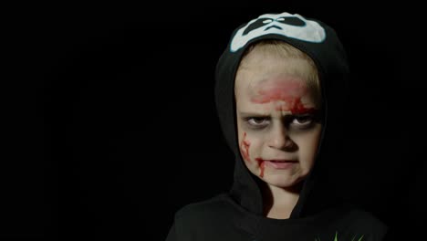 halloween, angry girl with blood makeup on face. kid dressed as scary skeleton, posing, making faces