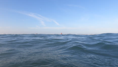 eye-level view of waves crashing on the shore at sunset