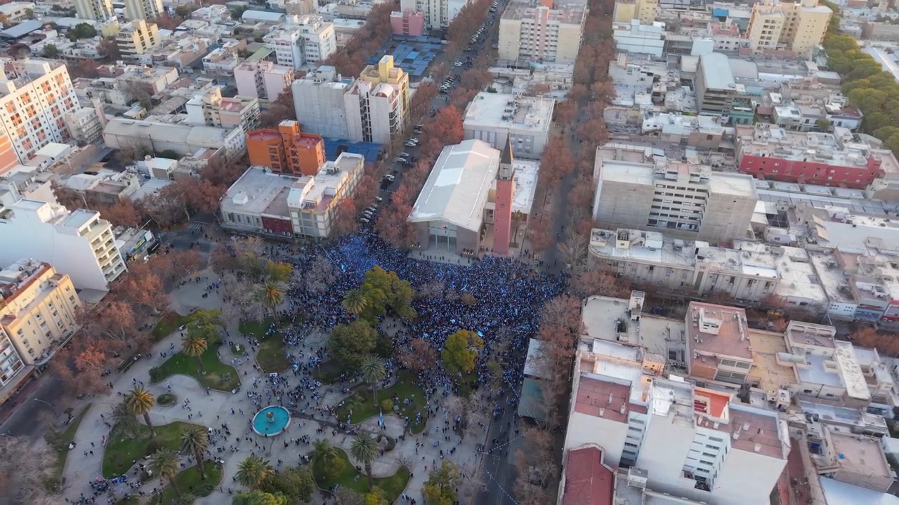 Ripresa aerea in allontanamento dall'alto che rivela grandi folle radunate intorno a Plaza 25 de Mayo, che celebrano il risultato calcistico dell'Argentina alla Coppa del Mondo FIFA
