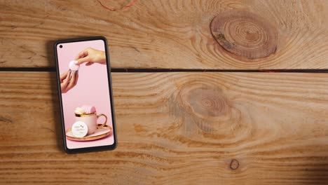 close up of hand picking up valentine's day gift next to mobile phone with valentines message on screen