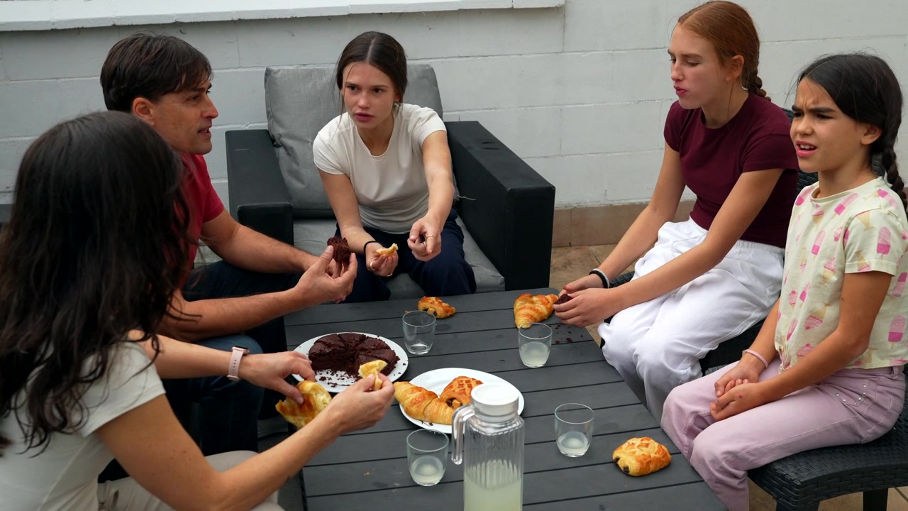 Familia disfrutando del desayuno juntos en un patio exterior.