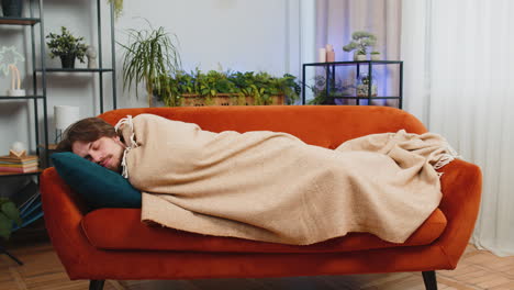 tired young man lying down on comfortable couch taking a rest daytime nap relaxing falling asleep