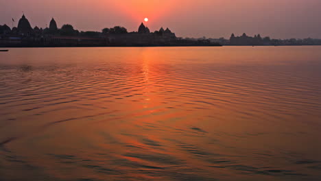 sunset over a river with ancient temples on the horizon