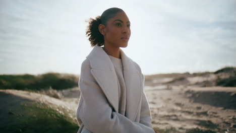 Pensive-woman-resting-beach-on-sunlight.-Serious-african-american-at-sand-dunes