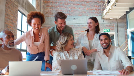 Retrato-De-Un-Equipo-De-Negocios-Multicultural-Reunido-Alrededor-De-Una-Computadora-Portátil-En-Una-Oficina-Ocupada