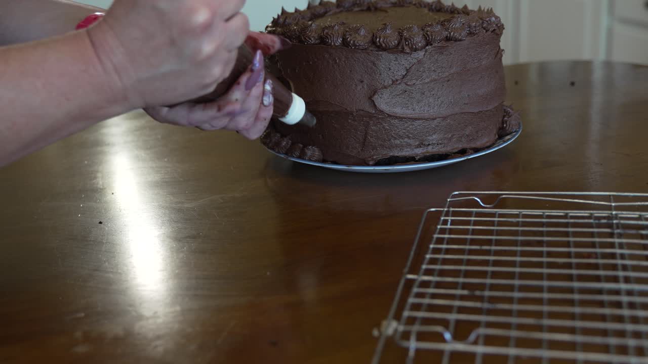 Mani di donna che decorano una torta al cioccolato a tre strati