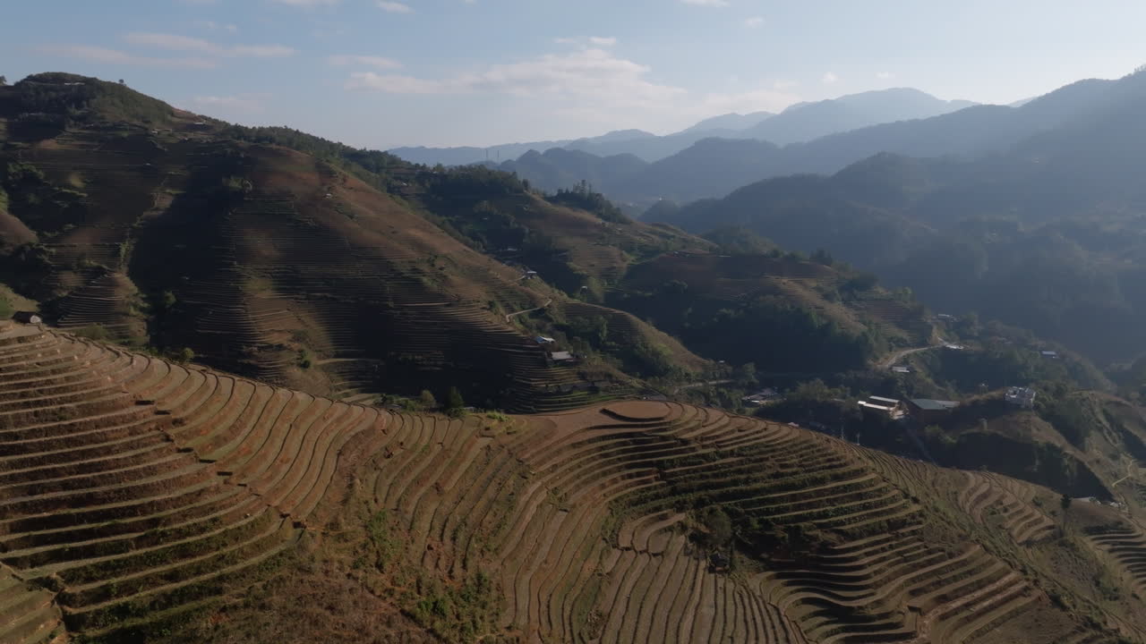 Bird's-eye footage revealing sweeping terrace curves and distant mountain ridges around Mui Giay (Mũi Giày), Mu Cang Chai, Yen Bai, Vietnam, capturing quiet countryside scenery