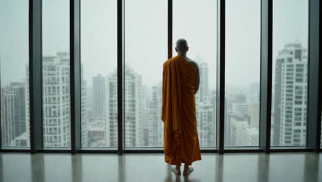monk contemplating cityscape from high-rise window