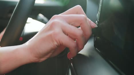 hand tuning fm radio button in modern car panel, looking for some nice music.