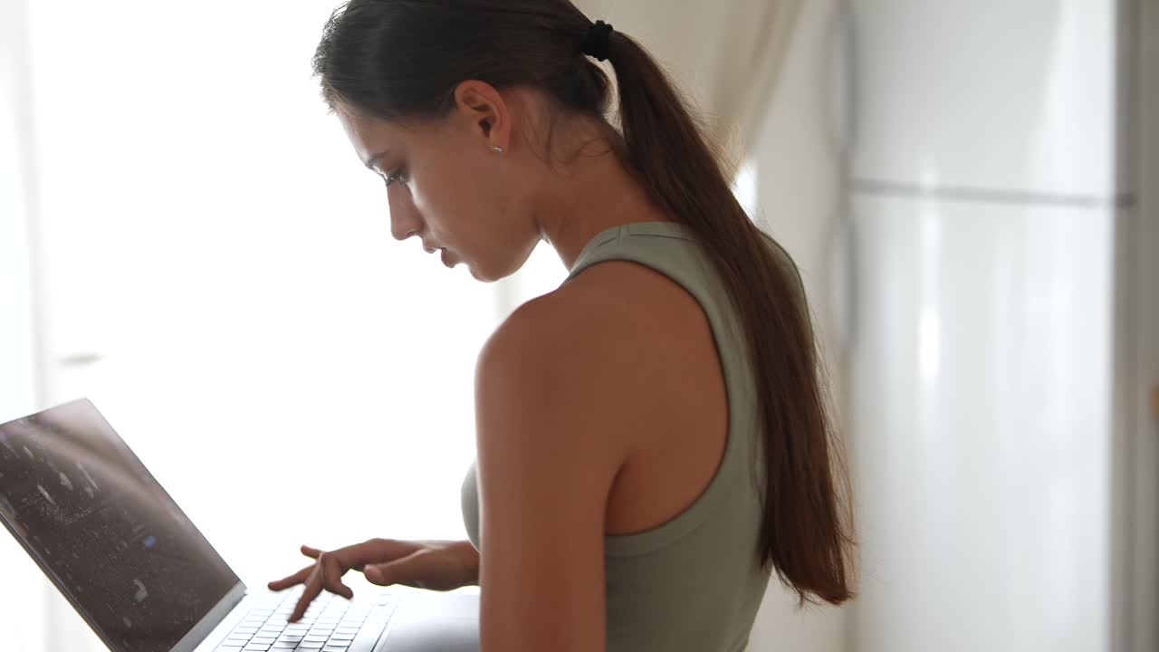 mujer joven trabajando en una computadora portátil en la cocina