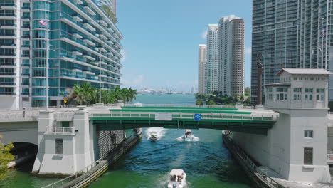Fly-over-road-bridge-above-river.-Revealing-view-of-modern-downtown-residential-towers-on-waterfront.-Miami,-USA