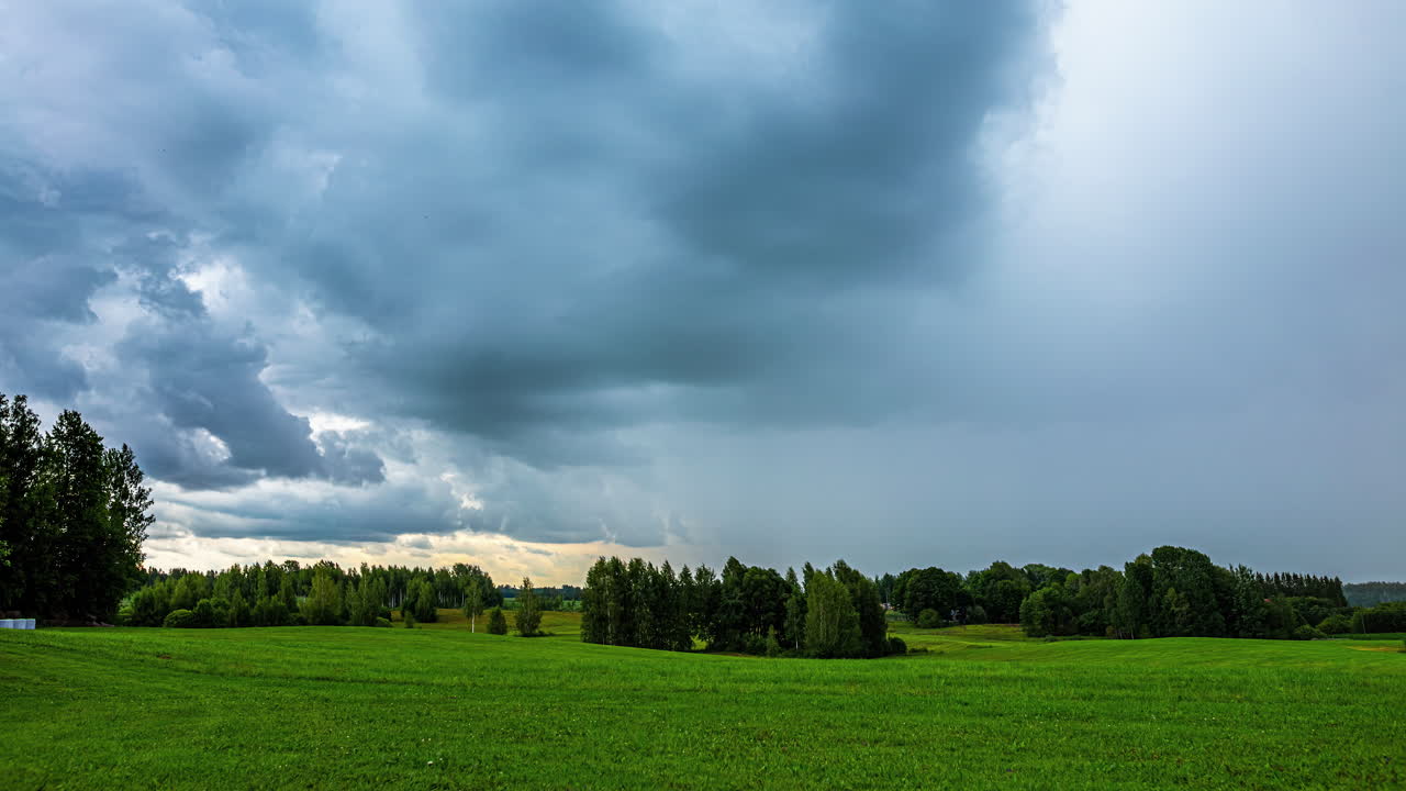 Dark, stormy rainclouds blow in over the countryside landscape - dramatic time lapse cloudscape