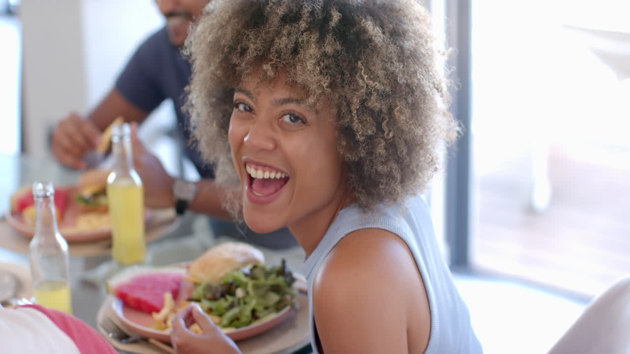 Smiling woman enjoying meal with Diverse friends, eating salad and sandwich at table