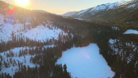 The-sun-rises-over-a-pine-forest-in-the-mountains-of-Tahoe-with-snow-on-the-ground