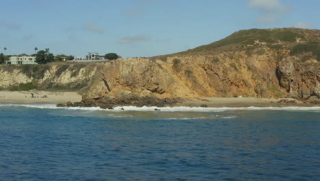 Arcing-shot-of-waves-crashing-onto-a-golden-sand-beach