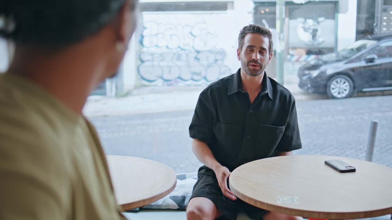 Primo piano di una coppia di uomini che si frequentano al ristorante, in una conversazione amichevole. Uomini gay che parlano.