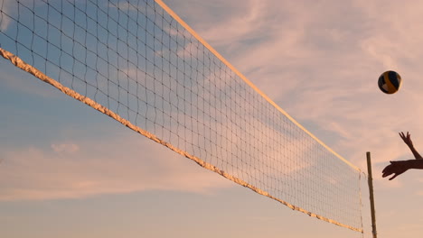 An-Einem-Schönen-Sommerabend-Springt-Ein-Sportliches-Mädchen-Beim-Beachvolleyball-In-Die-Luft-Und-Schlägt-Den-Ball-über-Das-Netz.-Eine-Kaukasische-Frau-Erzielt-Einen-Punkt.