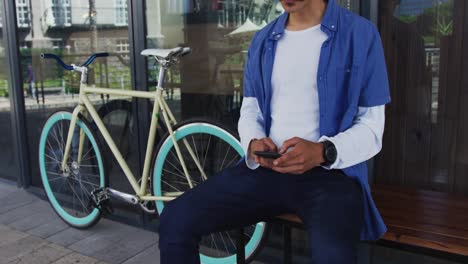 mixed race man with moustache sitting in street using smartphone