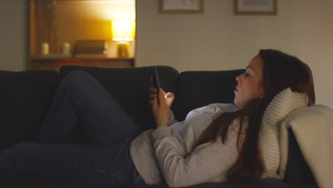 Close-Up-Of-Woman-Lying-On-Sofa-At-Home-At-Streaming-Or-Watching-Movie-Or-Show-Or-Scrolling-Internet-On-Mobile-Phone-9