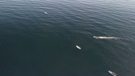 high aerial orbit around fishing boats in open ocean glistening water