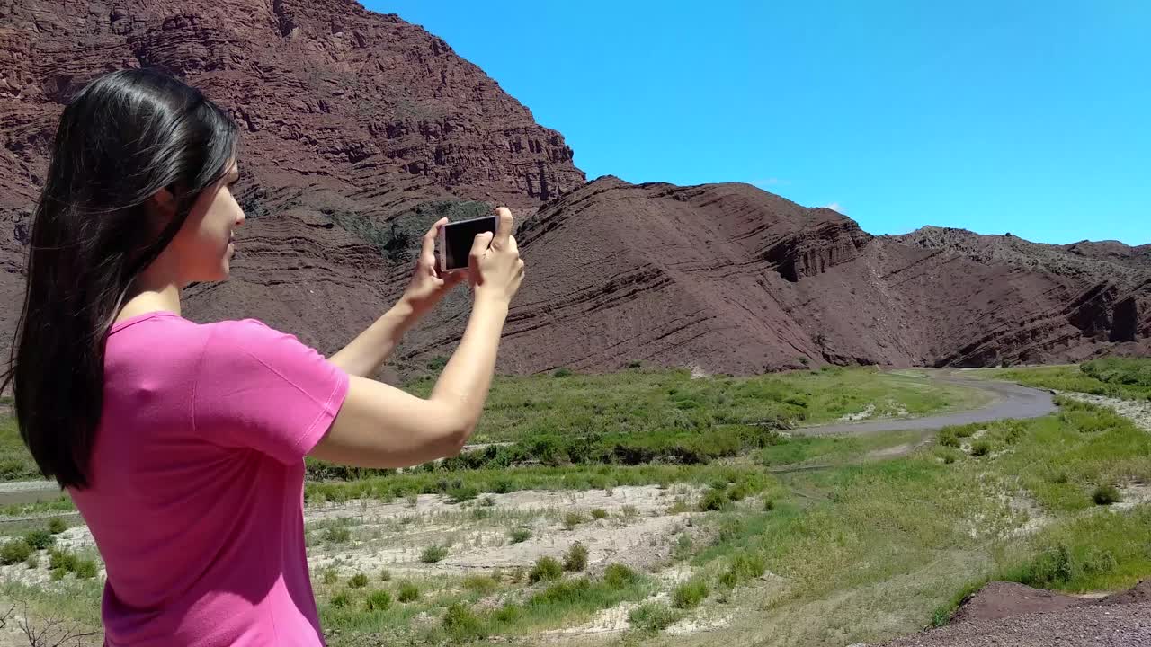 una joven usa su teléfono para tomar fotos de la quebrada de cafayate en argentina