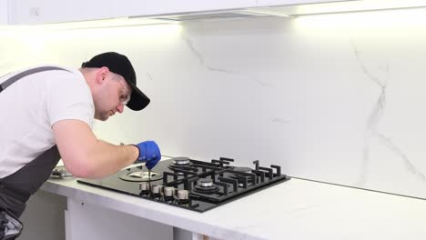 a gas engineer repairs a gas stove in the kitchen