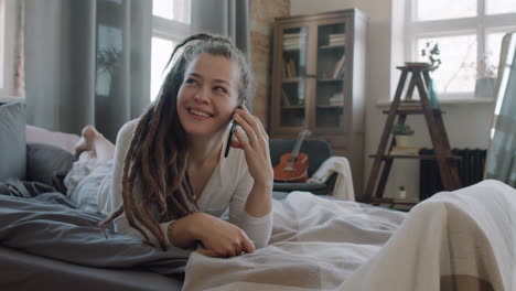 cheerful woman talking on phone in bed
