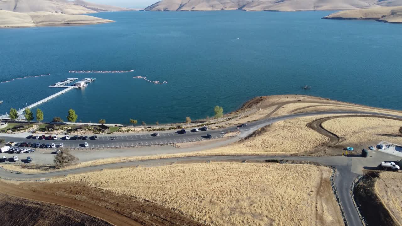 Traveling drone footage along waterside road revealing waterfront and road leading to the water