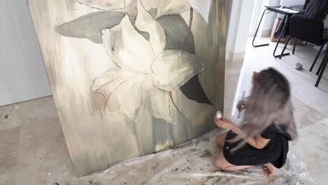 mujer latina arrodillada en el suelo y pintando hermosa pintura sobre lienzo