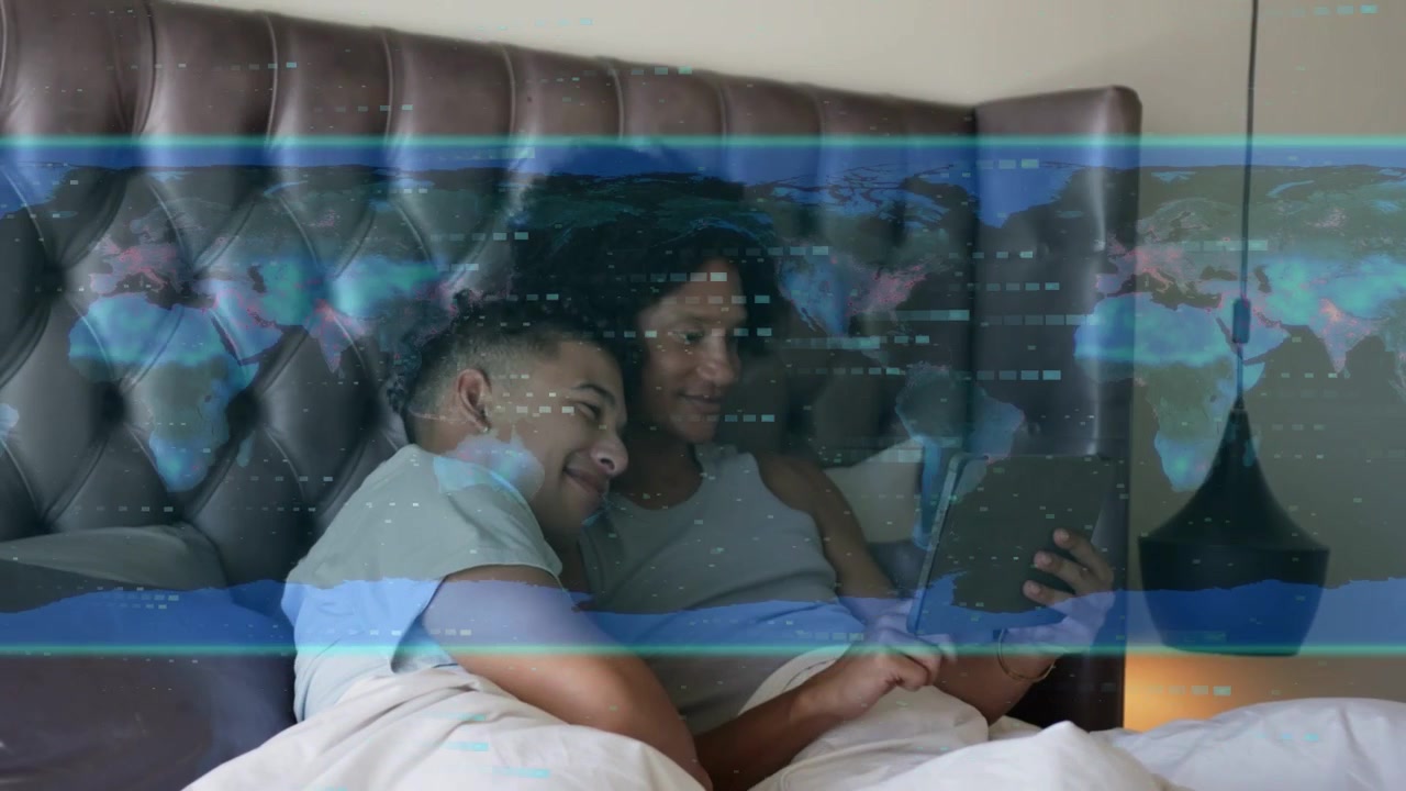 Due uomini sdraiati a letto, appoggiati l'uno all'altro, mentre scorrono un tablet, causando la dissolvenza di un'interfaccia tecnologica e sorridendo.