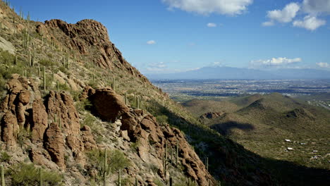 amazing drone shot of cacti covered mountain with tucson arizona in the distance