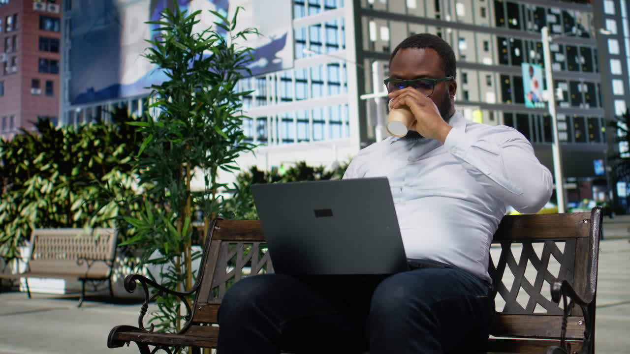 African american male working online from a bench in the park