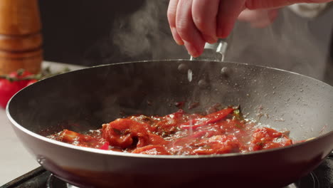 chef seasoning shrimp with tomato sauce