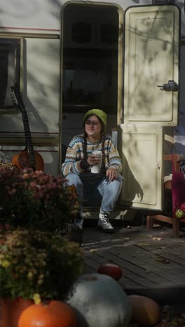 woman enjoying a warm drink in a campervan on a fall day.