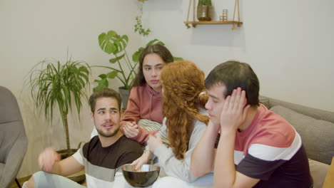 disappointed men and women sitting on sofa and supporting team