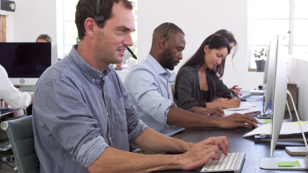 Colleagues with headsets on working at computers in office