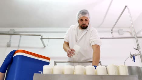 diary man passing the cheese into the molds - cheese production