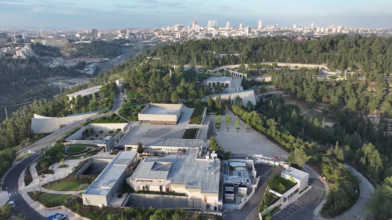 Prospettiva elevata del complesso del Centro di commemorazione dell'Olocausto Yad Vashem sul Monte Herzl, con lo skyline della città di Gerusalemme in lontananza.