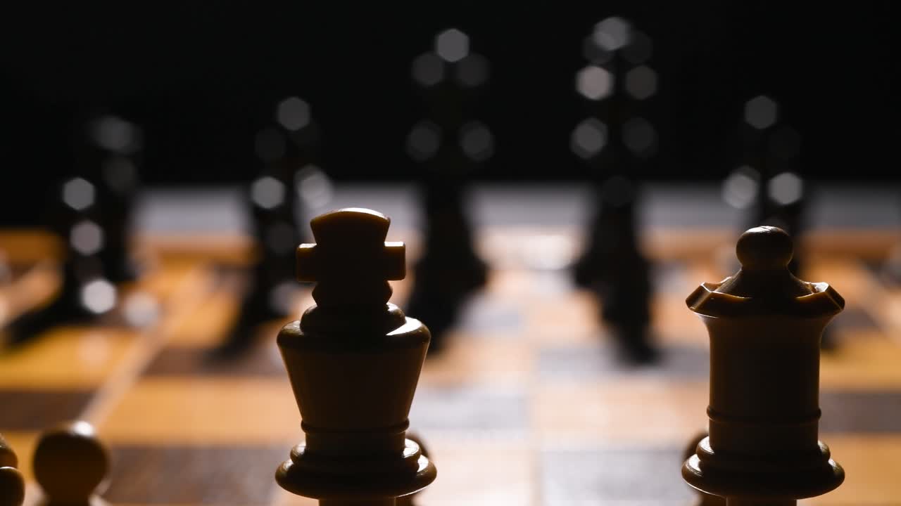 Cinematic roll shot of a chessboard with chess pieces on them, the background is out of focus and there is a light source illuminating the board and pieces from the back