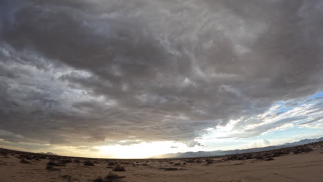 rain clouds form in the mojave desert sky then unleash a torrential downpour at sunset - dramatic time lapse