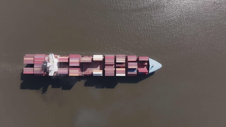 Cargo ship on a river followed by 2 tug boats