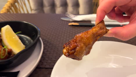 picking up a teriyaki chicken wing with spring onion and a lemon slice, tasty asian cuisine, 4k shot