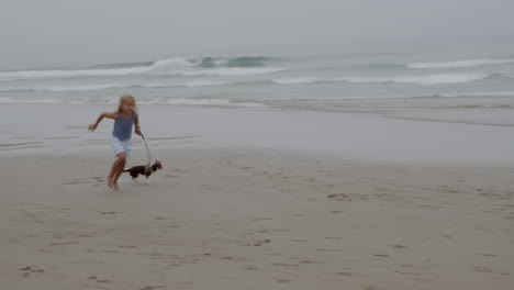 chica corriendo en la playa con su perro
