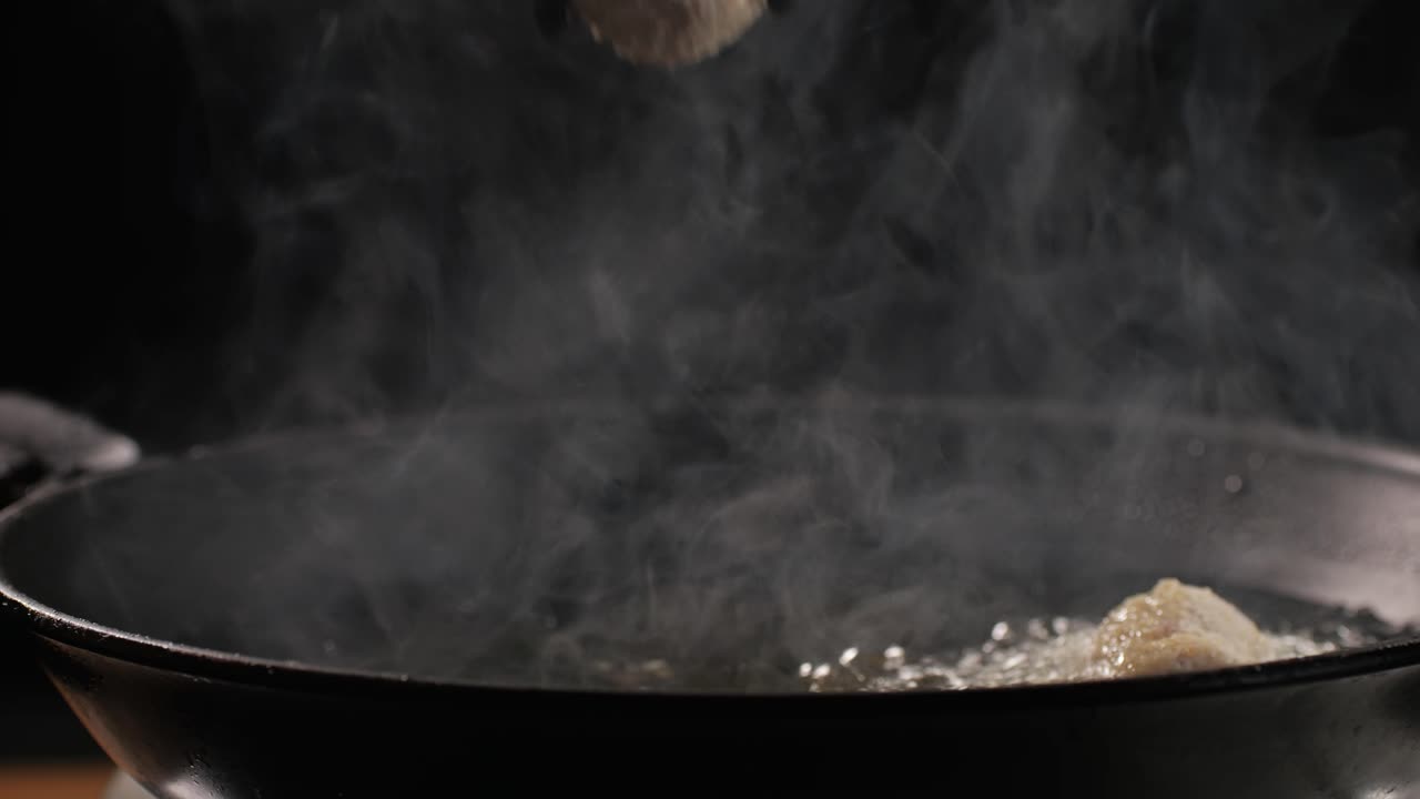 Portuguese croquettes broiling on black frying pan close-up macro. Breaded croquette of fish, potatoes and ham. Man cooking spanish food. High quality 4k footage