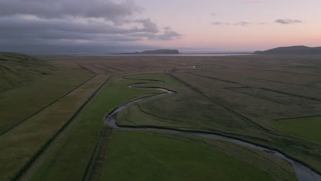 río de riego que fluye a través de campos de cultivo al atardecer