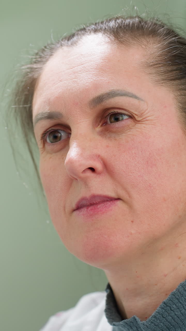 Primer plano clínico de una mujer de mediana edad con bata blanca sobre un fondo verde suave, secuencia de fotogramas de perfil y frontales que muestran la textura natural de la piel, poros visibles, pecas y finas arrugas.