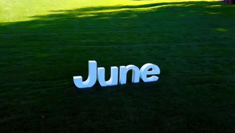 white letters spelling out june on a grassy field