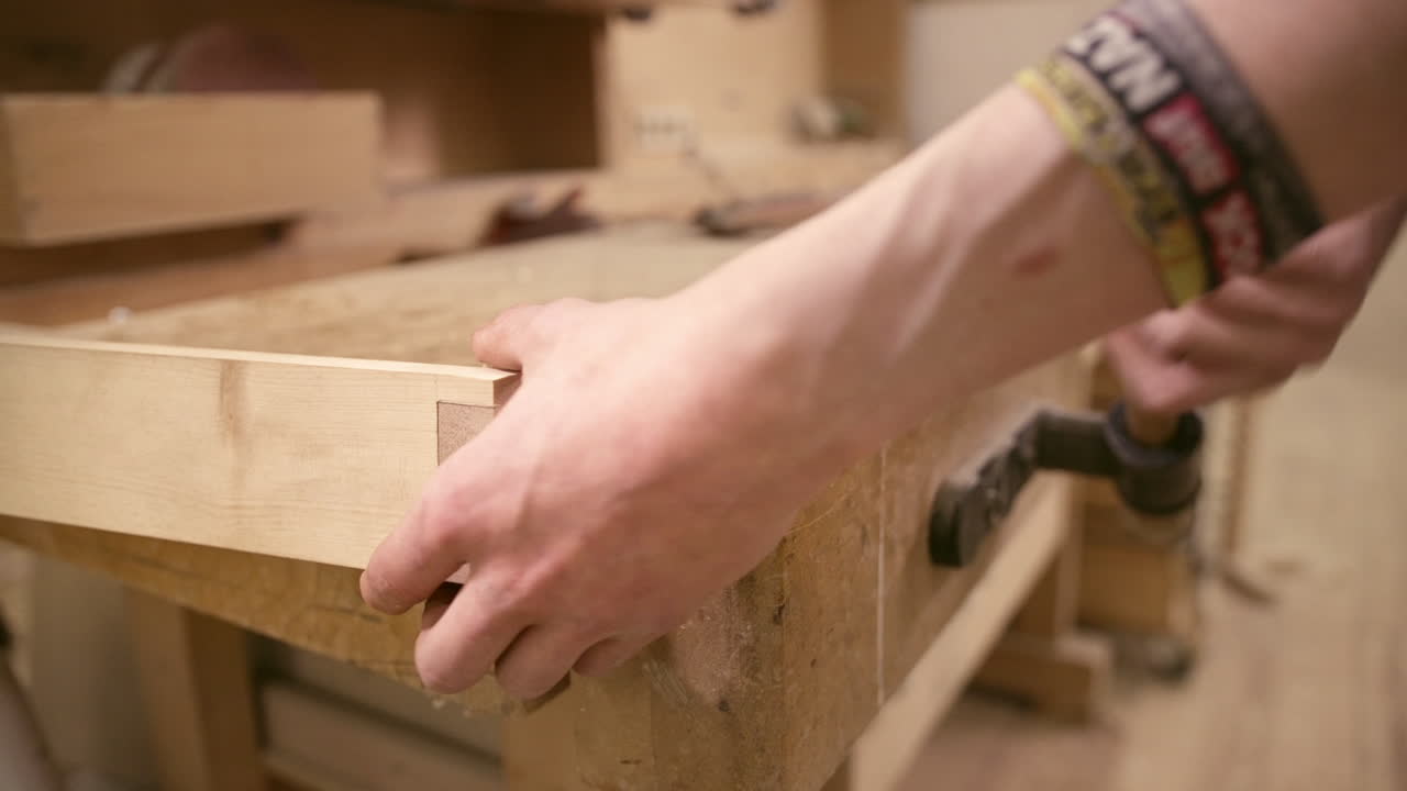 Carpenter clamping  a piece of wood in vise of wodden workbench. Working on furniture.
